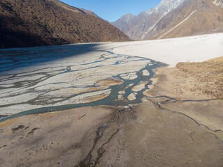 A breathtaking view of a mountain valley with a river flowing through a snowy landscape.
