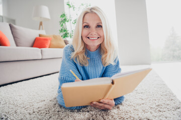Photo of pretty aged woman lying carpet floor write notebook wear pullover free time modern...
