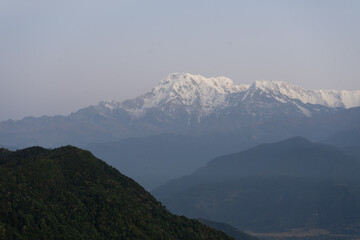 Snow-capped mountains overlooking a lush green valley at dawn.