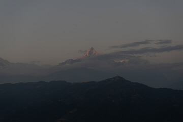 A serene mountain landscape at dusk with a peak subtly illuminated by the setting sun.