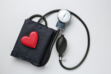 Blood pressure measuring device and heart figure on light grey background, top view