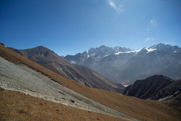 A breathtaking view of a mountain range with dry grassy slopes under a clear blue sky.