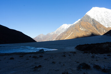 A serene mountain landscape with snow-capped peaks under a clear blue sky.
