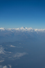 A breathtaking aerial view of snow-capped mountain peaks beneath a clear blue sky.