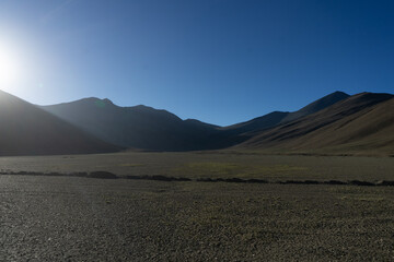 Sunrise casting light on a serene mountain landscape with clear blue skies.