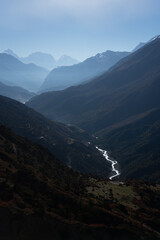 Naklejka premium A serene mountain range with a winding river reflecting sunlight.