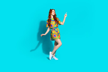 Full body photo of attractive young woman look point empty space dressed stylish colorful clothes isolated on cyan color background