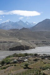 A serene mountain village with a view of majestic peaks under a clear blue sky.