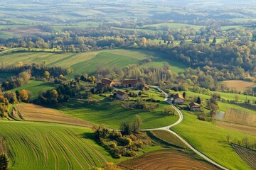 Naklejka premium A wide view captures rolling hills and sprawling farmlands interspersed with village homes in vivid greenery, depicting harmonious rural life against a vast countryside.