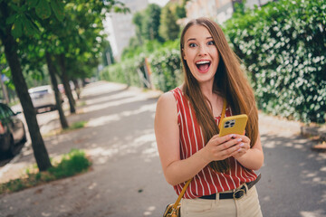 Photo of lovely positive adorable girl wear trendy clothes hold gadget summer time weather outdoors