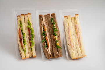 Three packaged sandwiches with white and whole wheat bread, filled with lettuce, tomatoes, turkey,...