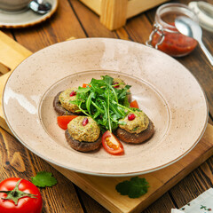 Fried champignons dish with walnut sauce and arugula in a plate, cafe, restaurant, wooden table.