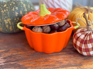 Pot of nuts, chestnuts and pumpkins on wooden old table. Composition for Halloween holiday. Autumn...
