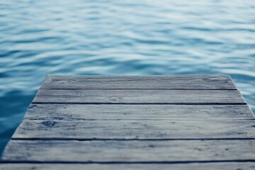 Fototapeta premium A sturdy wooden dock stretches into still, blue waters under a serene sky, inviting solitude and reflection, hinting at adventure and tranquility by the lakeside.