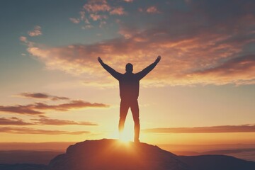 A man stands with raised arms atop a mountain during sunrise, embodying the spirit of adventure and triumph against a backdrop of colorful skies and vast horizon.