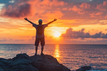 A person stands on a rocky seaside cliff, arms wide open, facing the brilliant sunset over the ocean, symbolizing exploration, freedom, and nature's beauty.