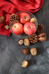 Seasonal composition with chestnuts, red juicy apples and nuts on gray background with space for text. Harvest festival concept. 