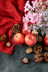 Autumn still life with apples, chestnuts and pine cones on dark background with space for text. 