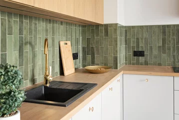 Fotobehang Hotel chique Kitchen interior in modern style with kitchen sink with tap, contemporary green tile on the wall, wooden counter and furniture. New apartment with design decor. Real estate.  © photosbysabkapl