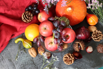Colorful still life with seasonal fruit and vegetables on fark grey textured background with copy space. Close up photo of pumpkin, apples, grape, chestnut, onion and squash. 