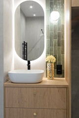 Luxury bathroom with glass to shower, round mirror with led lights, stylish washbasin and wooden...