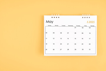 May 2025 desk calendar on yellow color background, position with copy space.