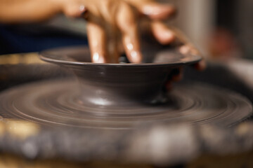 Hands of craftsman artist working on pottery wheel