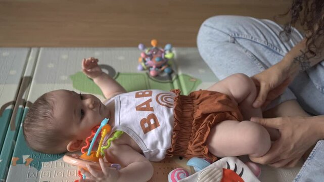Young mother playing with her baby daughter on a playmat. Young mother is bonding with her baby daughter while playing on a playmat