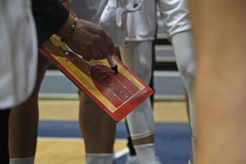 Basketball coach gives tactics to players on the clipboard