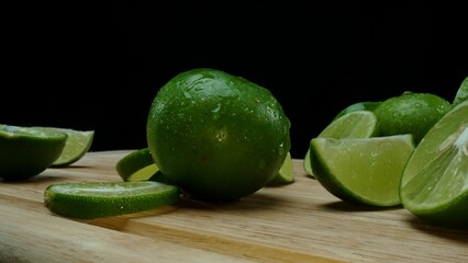 Close-up, a vibrant slice of fresh lime rests upon a rustic wooden cutting board, exuding freshness and vitality. The translucent membranes of the green lime slice placed on cutting board. Comestible.