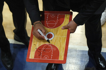 Basketball coach gives tactics to players on the clipboard