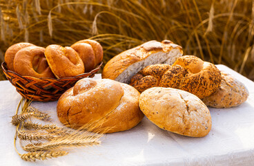 Lot of different flavored bread, wheat, rye, on the table in the field outside