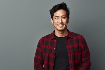 Obraz premium Portrait of a content asian man in his 30s wearing a comfy flannel shirt in front of soft gray background