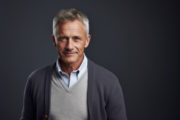 Obraz premium Portrait of a content man in his 50s wearing a chic cardigan in soft gray background