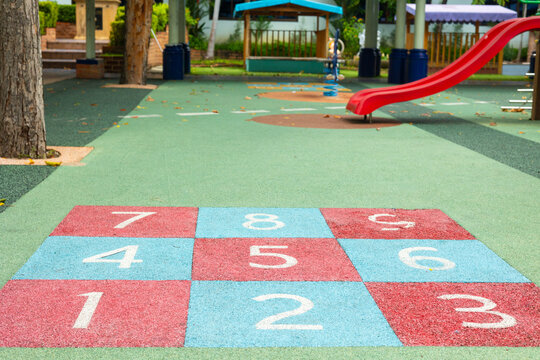 A colorful hopscotch grid sits in empty playground, inviting outdoor fun and physical activity. This vibrant children&rsquo;s play area promotes fitness and active play of childhood recreation in a park.