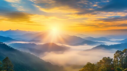 Obraz premium The image shows a beautiful sunrise over a misty mountain range. The sun is shining brightly, casting a golden glow over the landscape. The mountains are covered in a thick layer of fog, which give