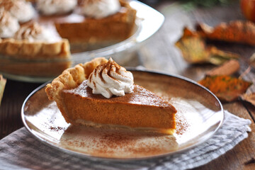 Traditional pumpkin pie topped with whipped cream. Selective focus.