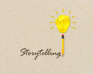 Yellow lightbulb made of crumpeld paper with pencil writing the word storytelling