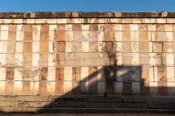 An old weathered temple wall painted in traditional red and white stripes in a village in Karnataka in South India.