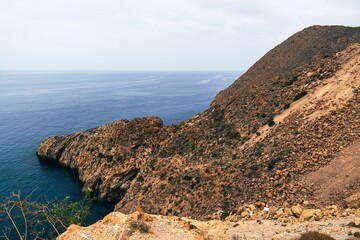Scenic view of a rocky coastline with a vast ocean under a cloudy sky
