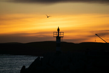 Fototapeta premium Aatardecer en el Puerto de Camarones, en la Patagonia Argentina, provincia de Chubut, donde se puede apreciar el característico faro. 