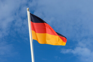 Waving German flag against a clear blue sky on a sunny day, symbolizing national pride and identity in Germany