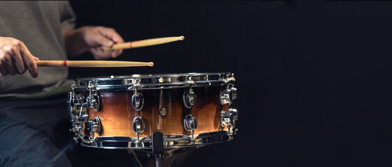 A man plays a drum. Drumsticks are hit on the drum. Copy space.