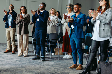 Diverse group of coworkers applauding at a business conference presentation