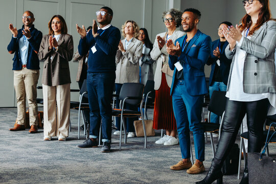 Diverse group of coworkers applauding at a business conference presentation