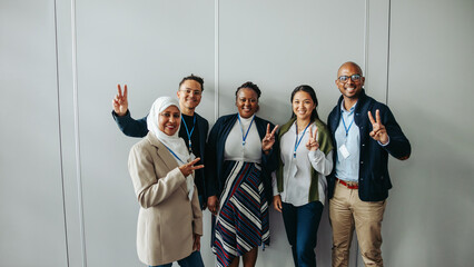 Colleagues posing with peace signs showcasing teamwork and diversity in a bright office environment