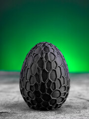 Close-up of a plastic egg model with ornament on a green background