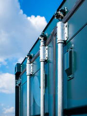 Close-up of a cargo container door featuring three sturdy metal pipes securing the door, showcasing the industrial design and functionality essential for logistics and freight transportation.