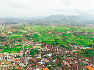 Aerial drone view of Muslim Balinese settlements near green paddy fields scenery at Gelgel Village in Klungkung, Bali, Indonesia.