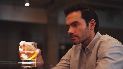 Sitting smart man drinking alone of cocktail Old fashioned waiting friends or couple at bokeh lighting at luxurious beverage counter nightclub at pub and restaurant on Friday meeting night. Vinosity.